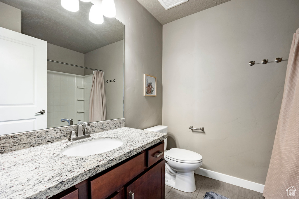Bathroom featuring toilet, vanity, a textured ceiling, tile patterned flooring, and baseboards