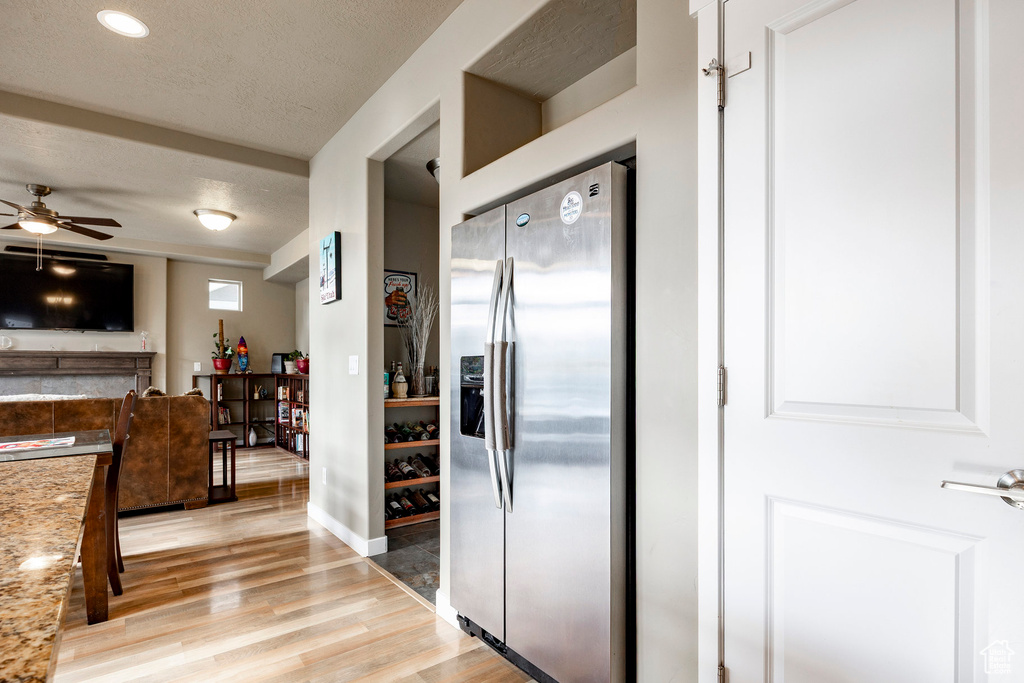 Kitchen featuring a textured ceiling, stainless steel refrigerator with ice dispenser, ceiling fan, light countertops, and light wood-style floors