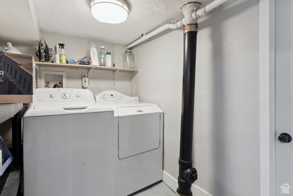 Clothes washing area with laundry area, washer and clothes dryer, and a textured ceiling
