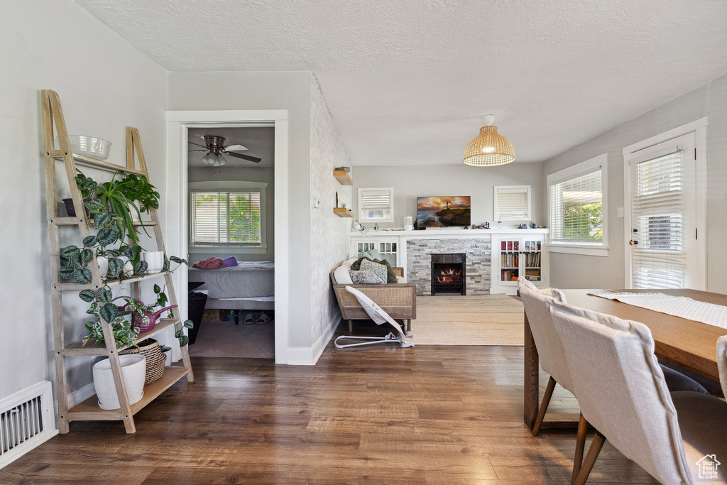 Dining area with a ceiling fan, baseboards, visible vents, wood finished floors, and a fireplace
