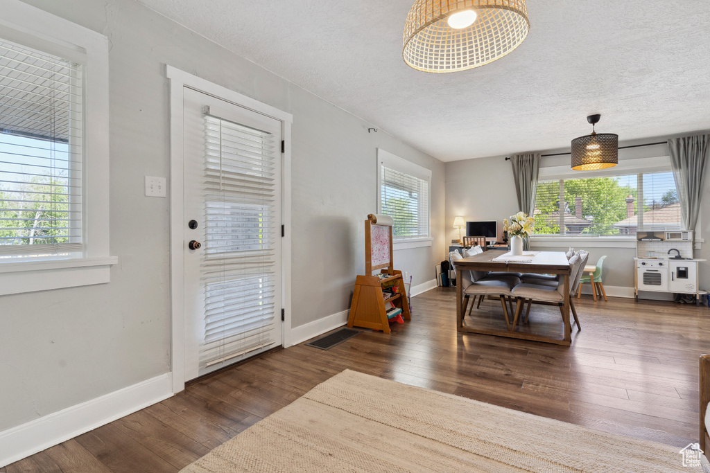 Dining space with a textured ceiling, baseboards, visible vents, and wood finished floors