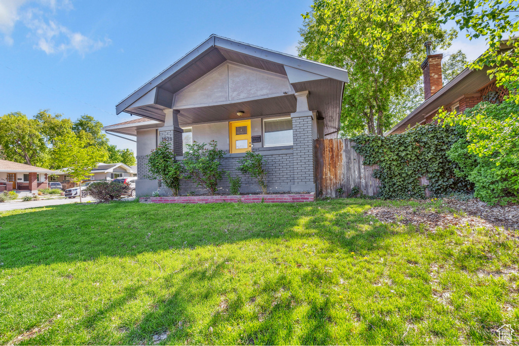 View of front facade featuring fence, brick siding, and a front yard