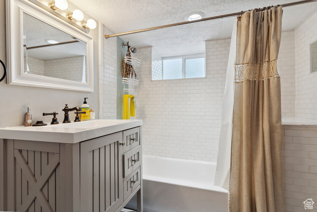 Bathroom featuring vanity, a textured ceiling, and shower / bath combo