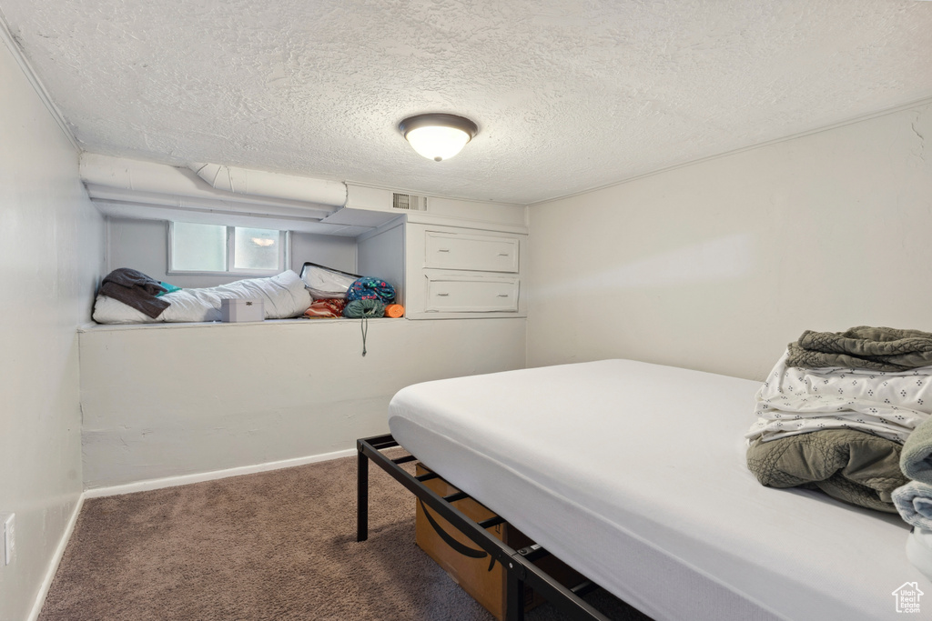 Bedroom with baseboards, dark carpet, visible vents, and a textured ceiling