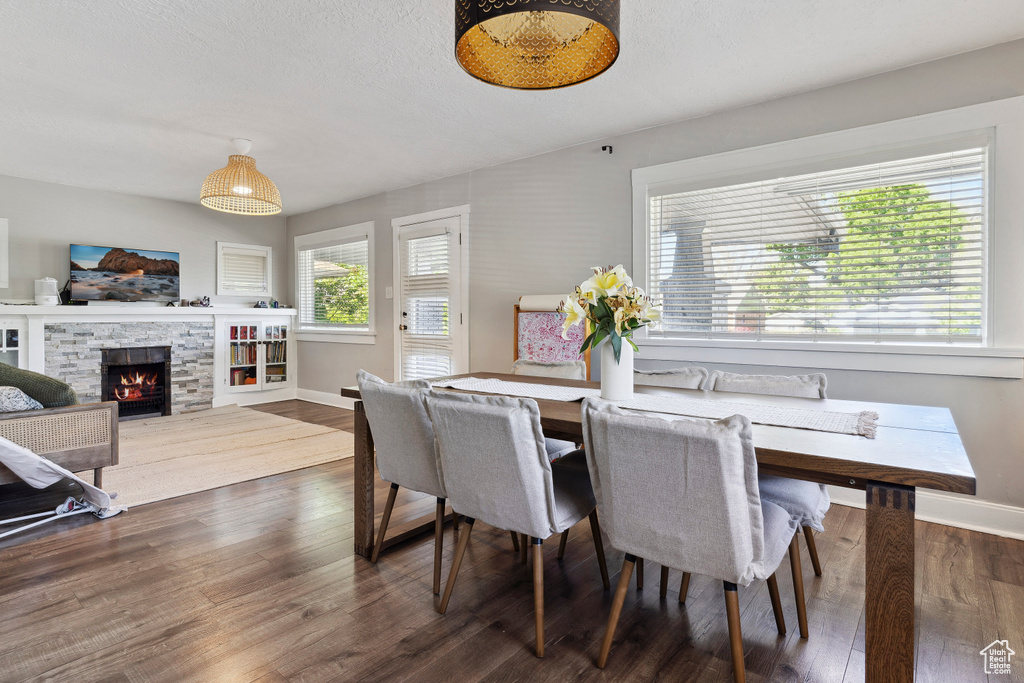 Dining space featuring a fireplace, baseboards, and dark wood-type flooring