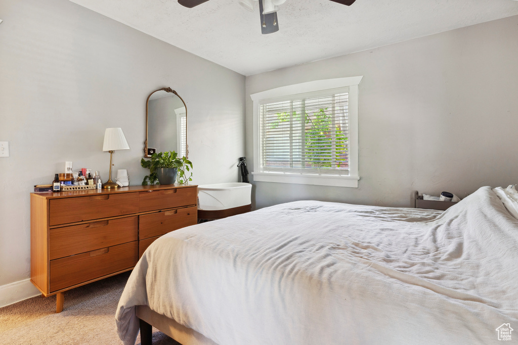 Bedroom with light colored carpet, baseboards, and a ceiling fan