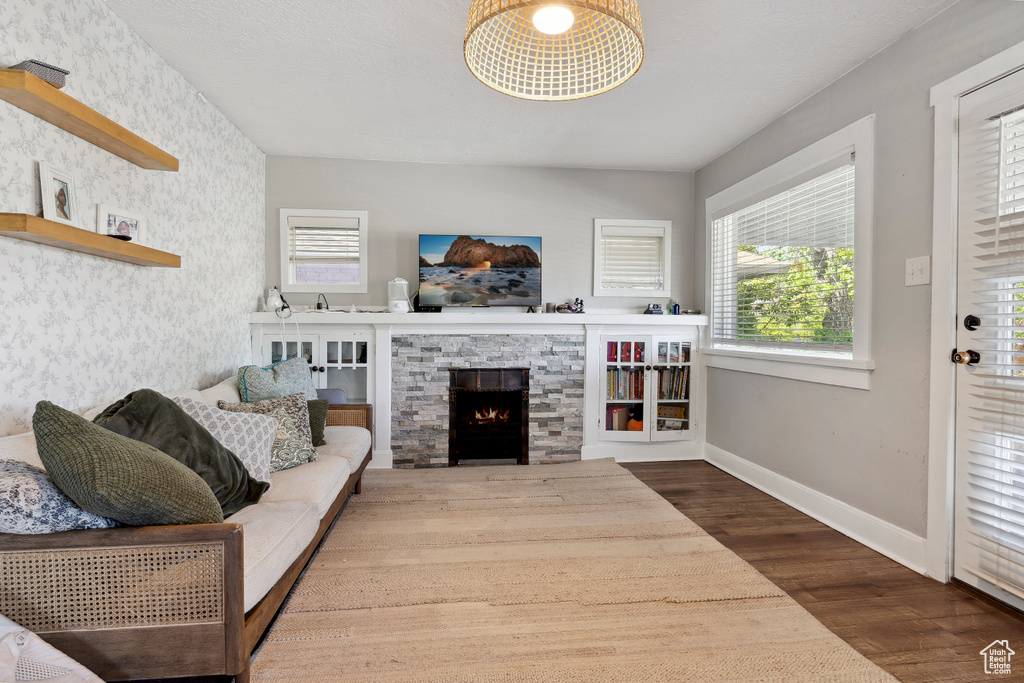 Living room with wood finished floors, baseboards, and a stone fireplace