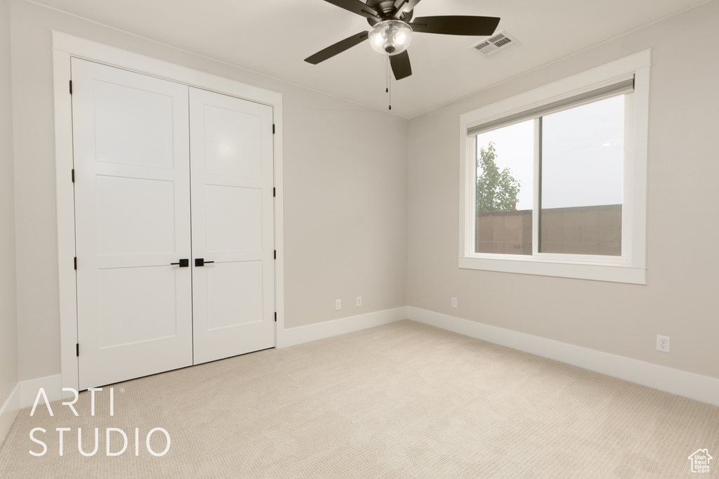Unfurnished bedroom featuring light colored carpet, baseboards, a closet, and a ceiling fan