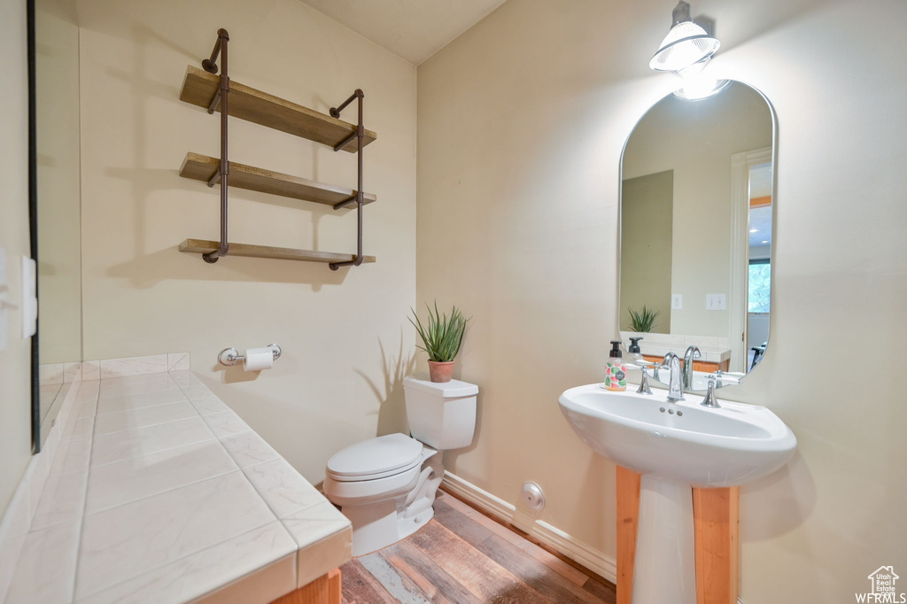 Half bathroom featuring toilet, a sink, and wood finished floors