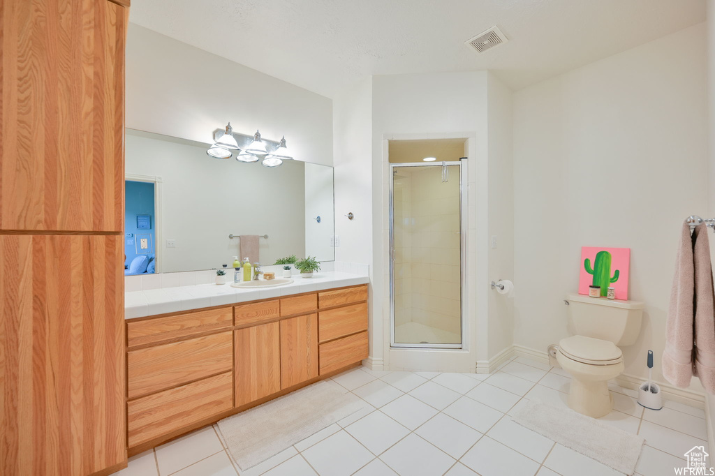 Full bath with toilet, vanity, visible vents, tile patterned flooring, and a shower stall