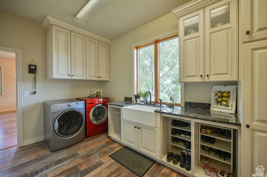 Laundry area featuring a sink, cabinet space, washing machine and clothes dryer, dark wood-style flooring, and baseboards