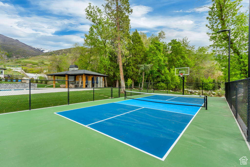 View of tennis court featuring a gazebo, fence, and a mountain view
