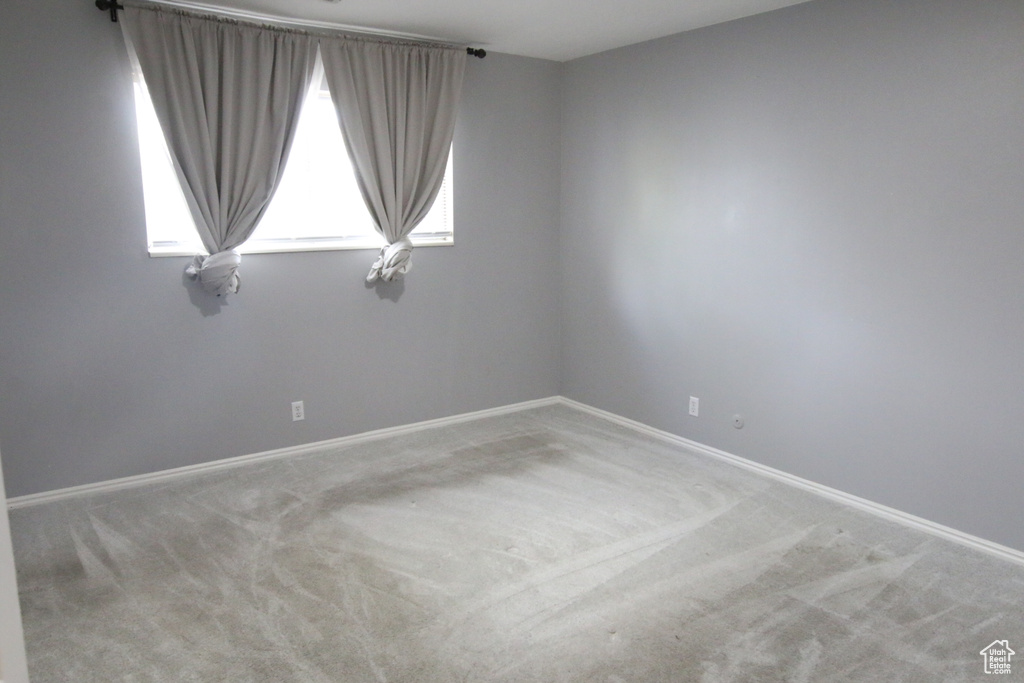 Carpeted spare room featuring baseboards