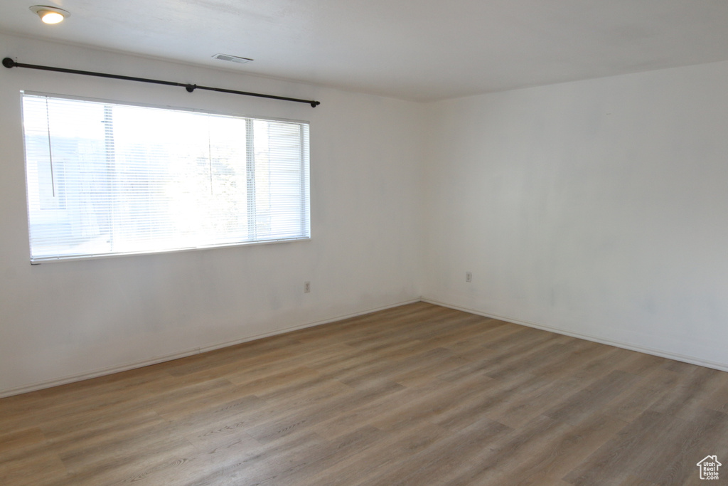 Spare room with light wood finished floors, visible vents, and baseboards