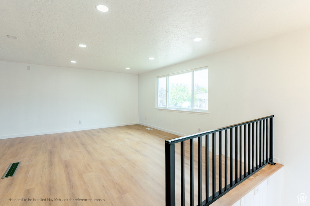 Unfurnished room with a textured ceiling, visible vents, recessed lighting, light wood finished floors, and baseboards