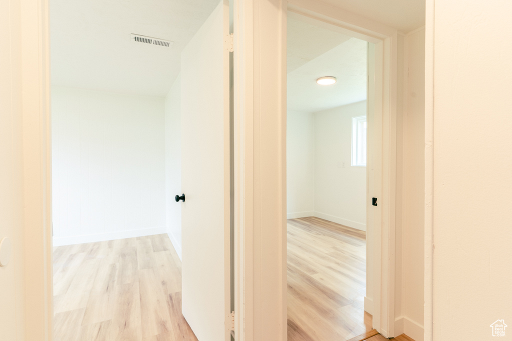 Corridor featuring light wood-style flooring, baseboards, and visible vents