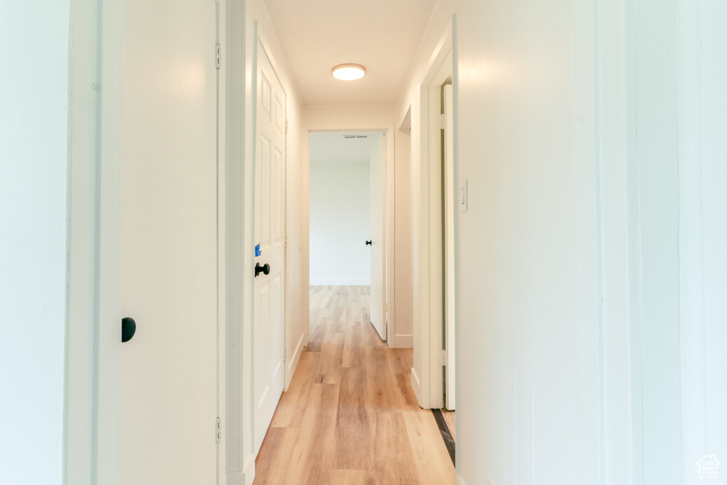 Hallway featuring light wood-style flooring and baseboards
