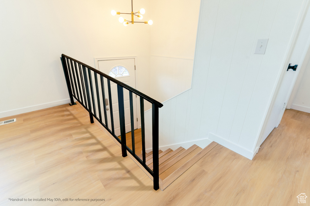 Stairs featuring an inviting chandelier, baseboards, visible vents, and wood finished floors