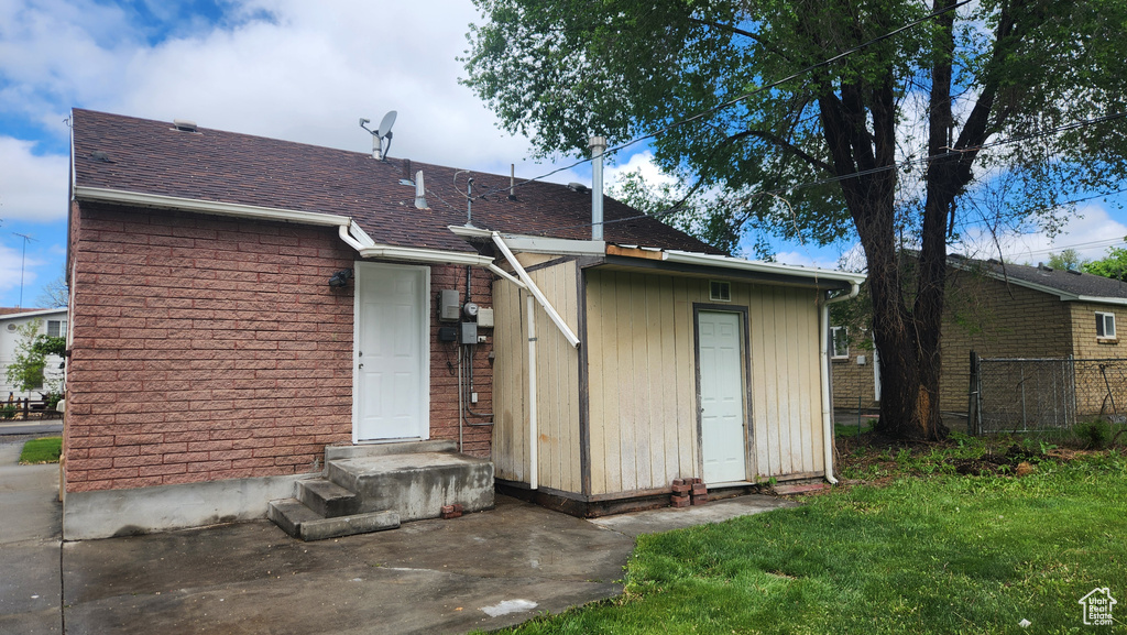 Back of property featuring a yard, roof with shingles, and fence