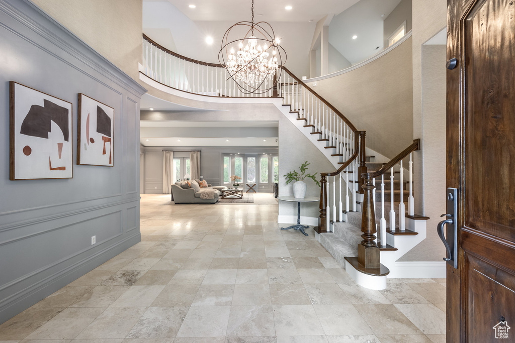 Foyer with an inviting chandelier, stairway, baseboards, a towering ceiling, and recessed lighting