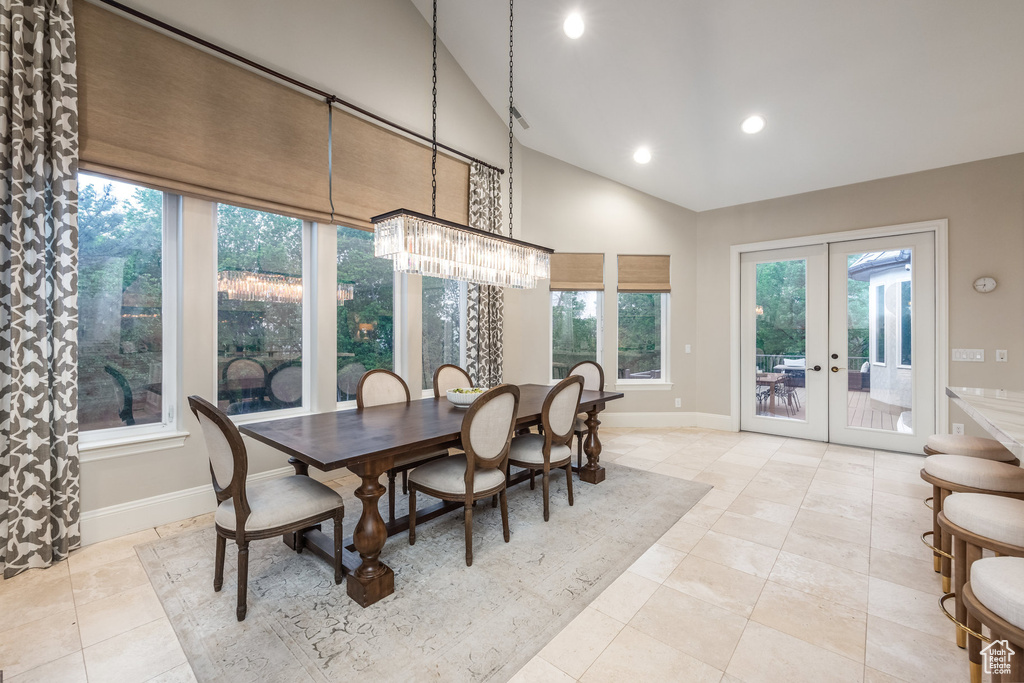 Dining space featuring french doors, a notable chandelier, tile patterned floors, baseboards, and vaulted ceiling