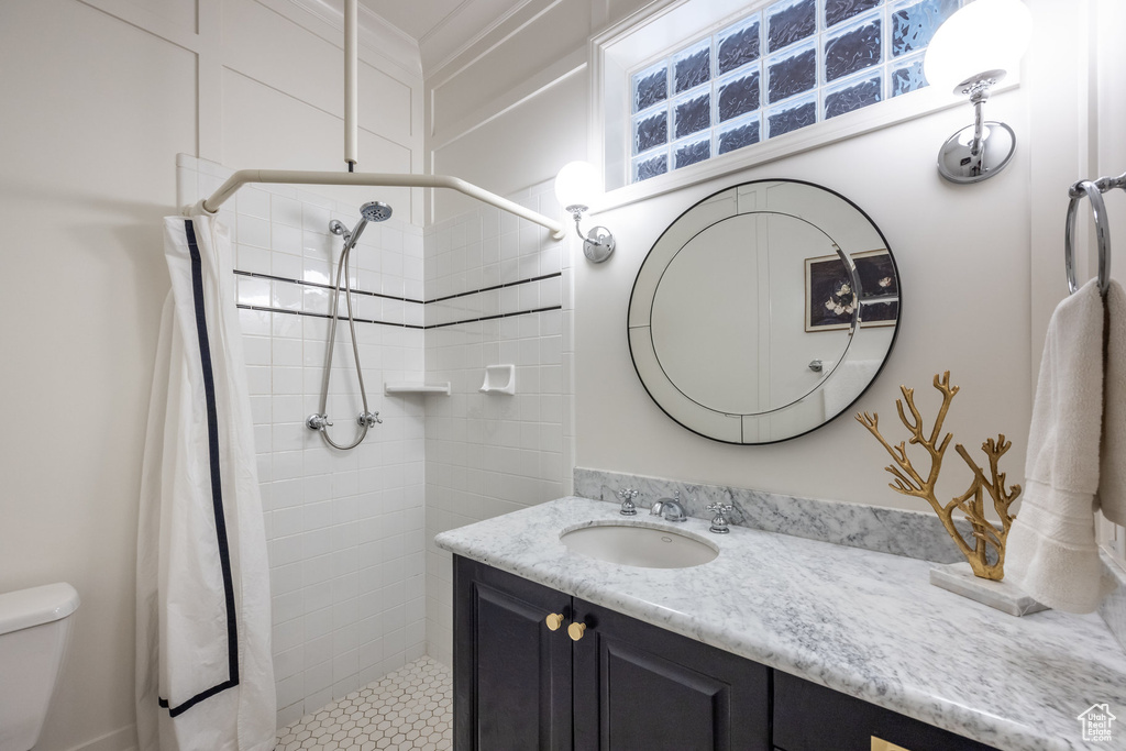 Bathroom with toilet, vanity, and tiled shower