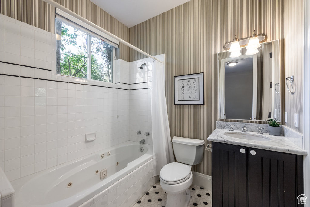 Bathroom featuring a combined bath / shower with jetted tub, vanity, toilet, and wallpapered walls