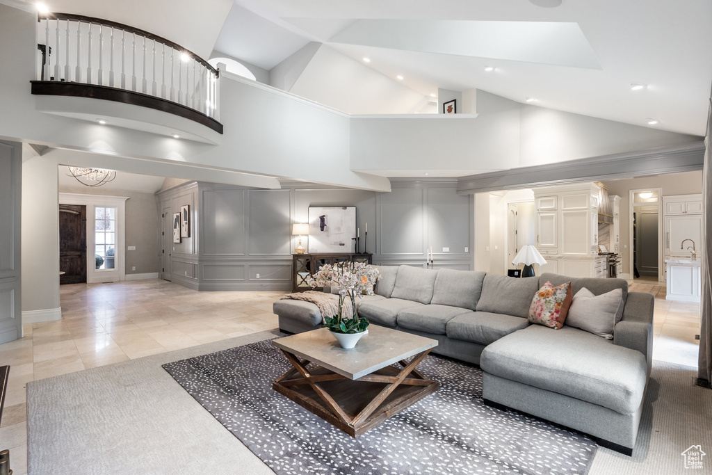Living area featuring recessed lighting, a decorative wall, baseboards, and high vaulted ceiling