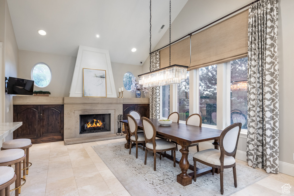 Dining space featuring a fireplace, lofted ceiling, baseboards, and recessed lighting