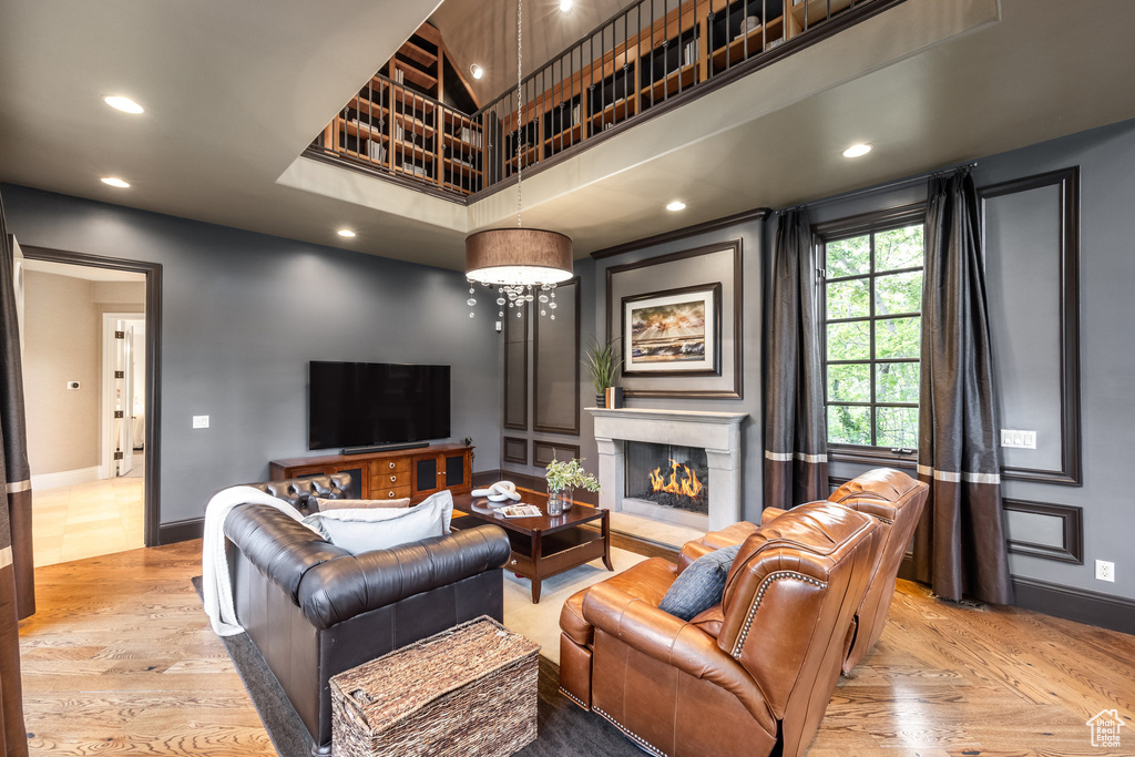 Living room featuring baseboards, recessed lighting, a towering ceiling, and wood finished floors