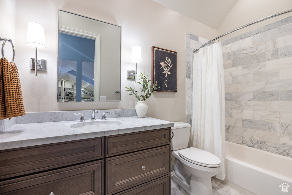 Bathroom with vanity, toilet, lofted ceiling, and shower / bathtub combination with curtain