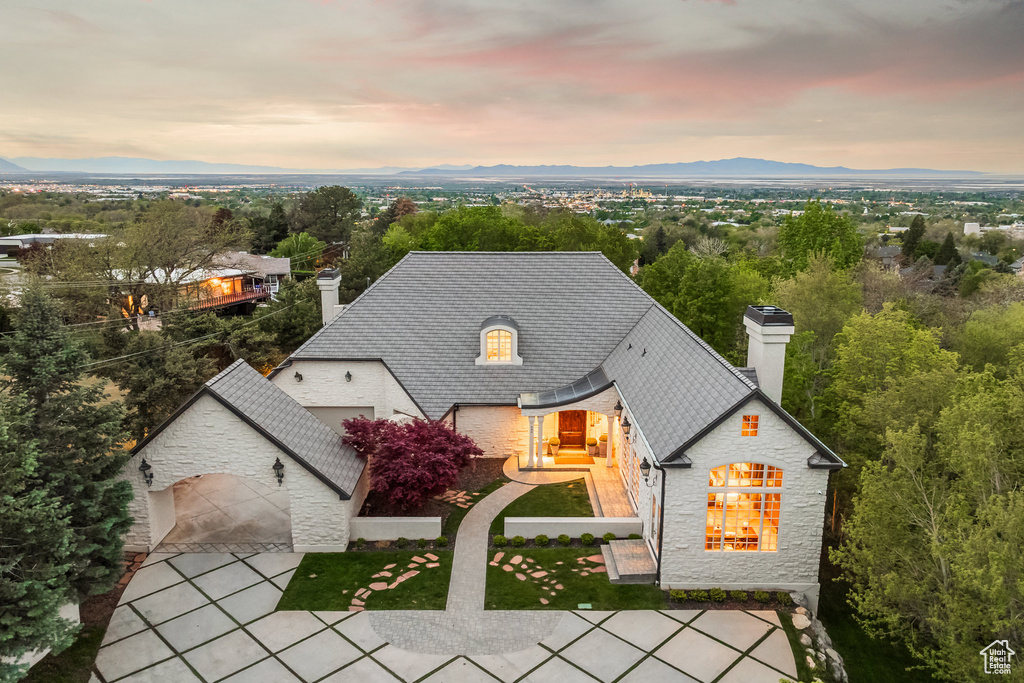 View of front of property featuring stone siding, a mountain view, a chimney, and driveway