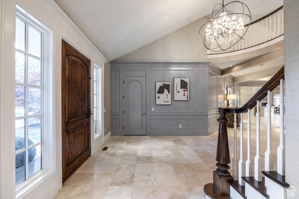 Entryway featuring vaulted ceiling, an inviting chandelier, a decorative wall, and plenty of natural light