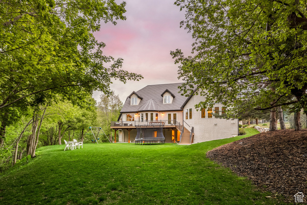 Back of property featuring a yard, a deck, stairway, and stucco siding
