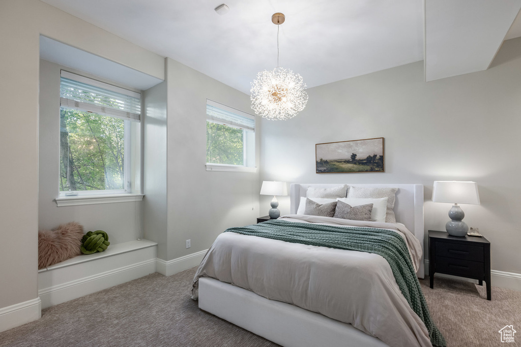 Carpeted bedroom featuring a chandelier and baseboards