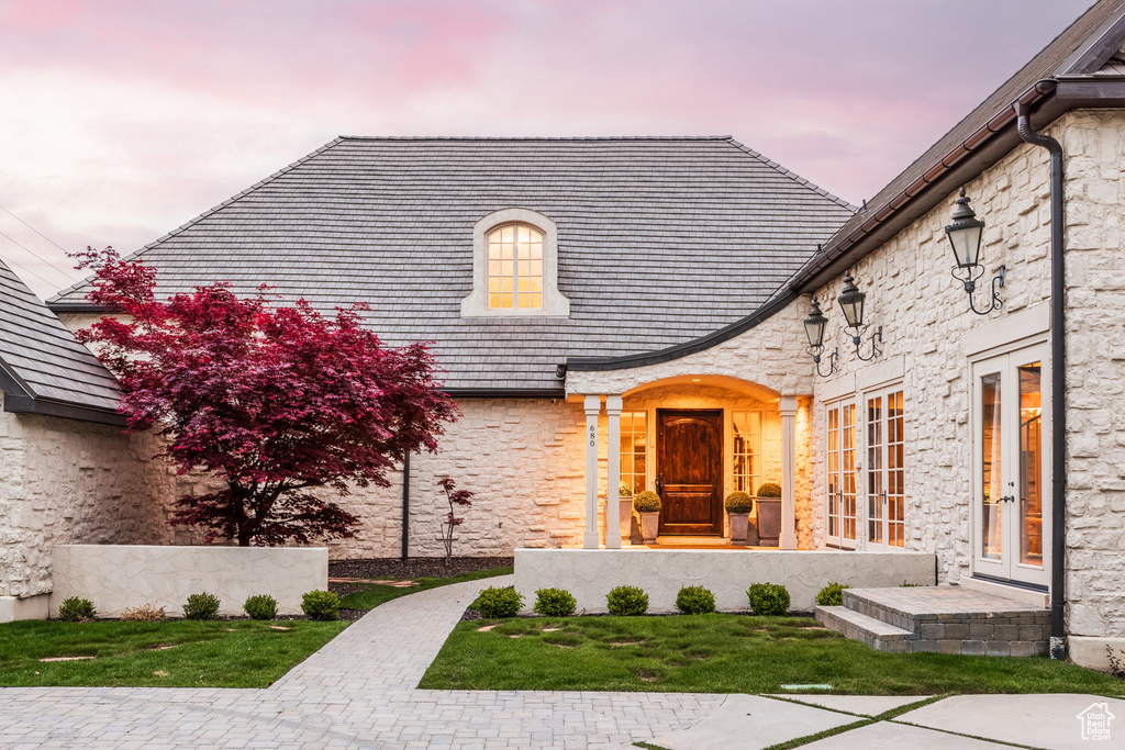 Entrance to property featuring stone siding, a high end roof, and french doors