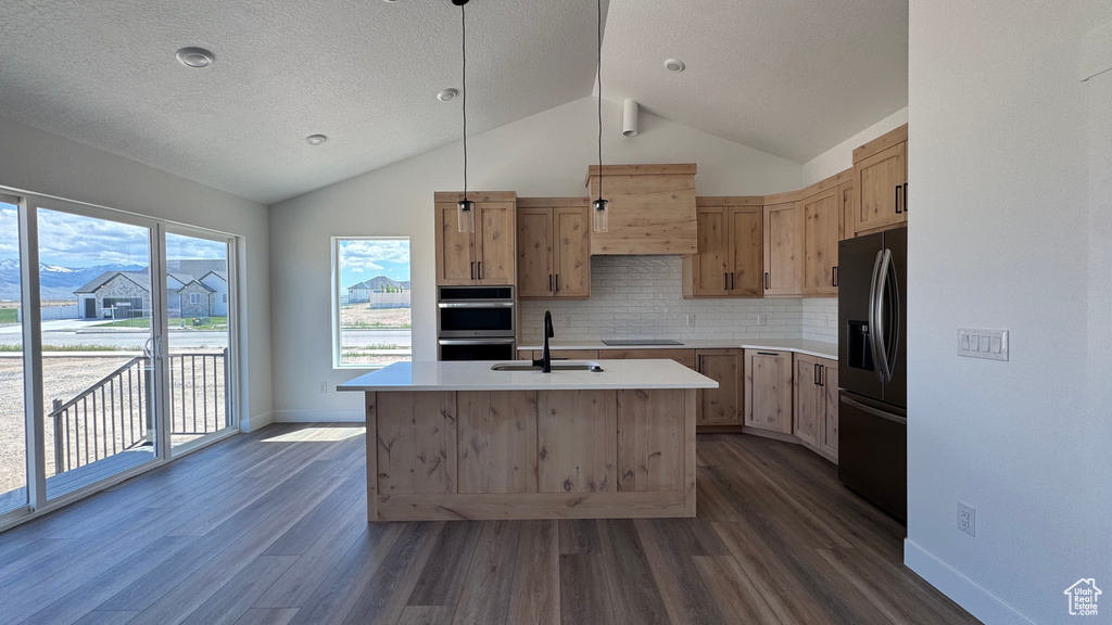 Kitchen with fridge with ice dispenser, a sink, dark wood finished floors, vaulted ceiling, and backsplash