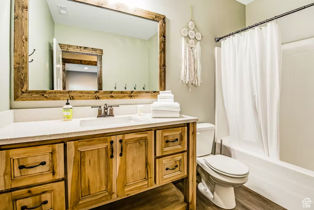 Full bathroom with shower / tub combo with curtain, vanity, toilet, and wood finished floors