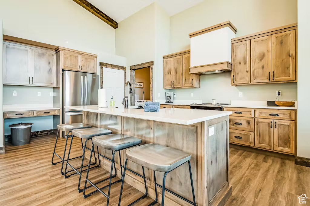 Kitchen with a center island with sink, light wood-style flooring, a breakfast bar, and high vaulted ceiling