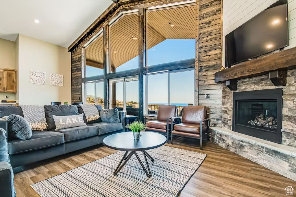 Living room featuring high vaulted ceiling, a stone fireplace, and wood finished floors