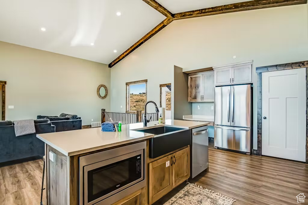 Kitchen featuring a sink, stainless steel appliances, an island with sink, and wood finished floors