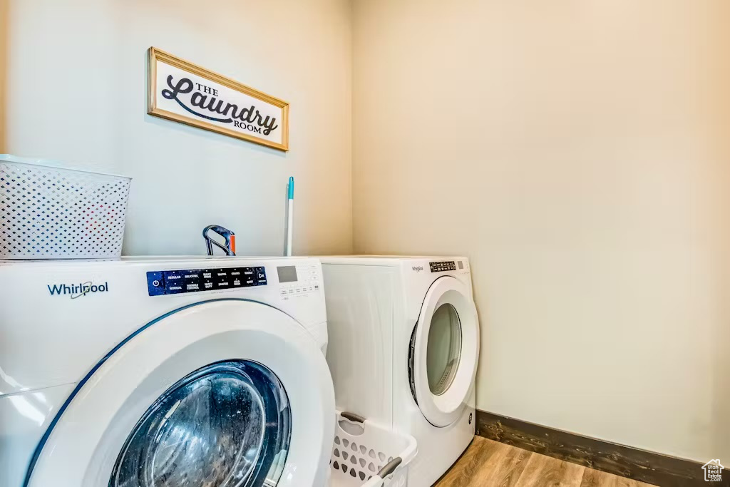 Laundry room with baseboards, separate washer and dryer, laundry area, and wood finished floors