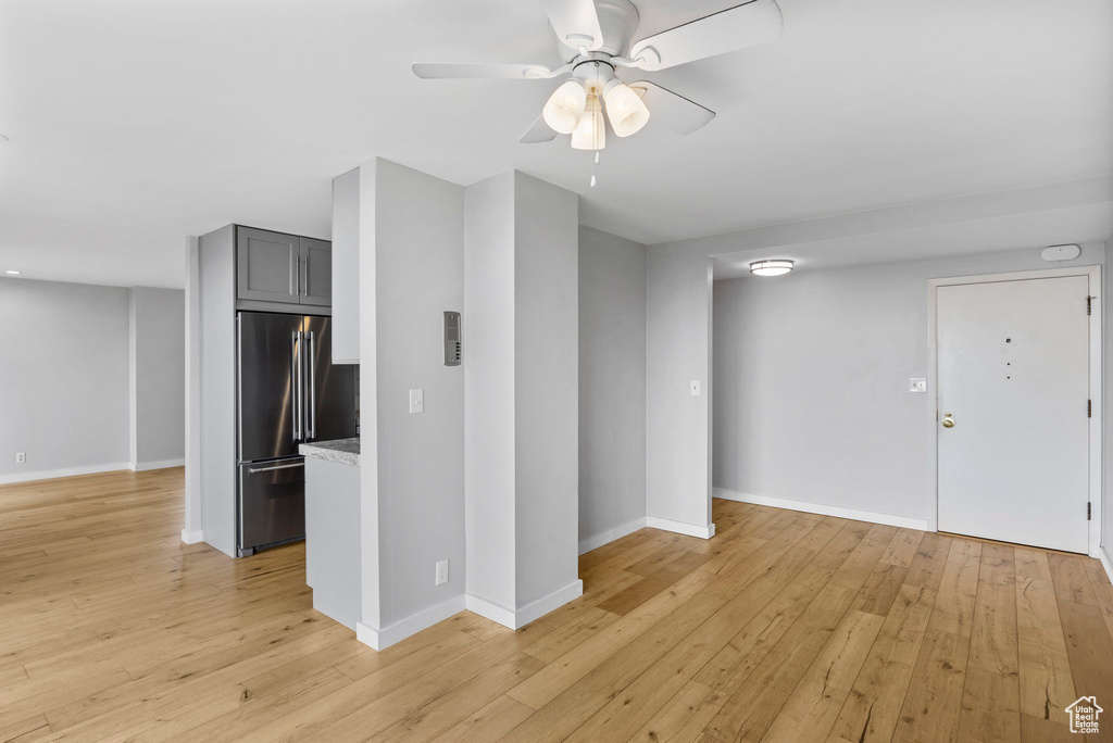 Unfurnished living room featuring light wood-style flooring, baseboards, and ceiling fan