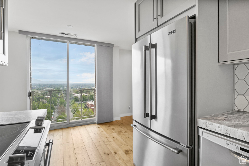Kitchen featuring gray cabinetry, appliances with stainless steel finishes, visible vents, and light wood-style floors