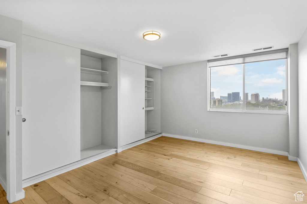 Unfurnished bedroom featuring a closet, visible vents, baseboards, and hardwood / wood-style floors