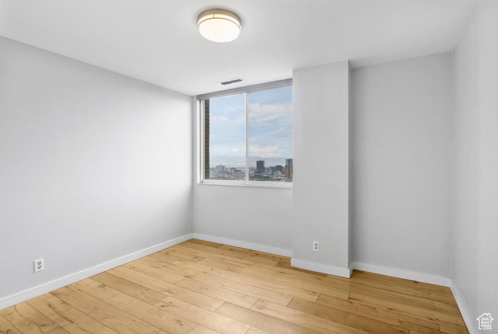 Spare room featuring light wood-style flooring, baseboards, and visible vents