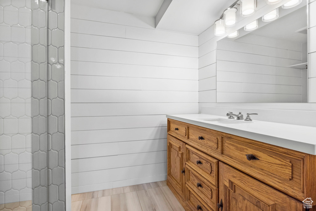 Bathroom with vanity, tiled shower, and wood finished floors