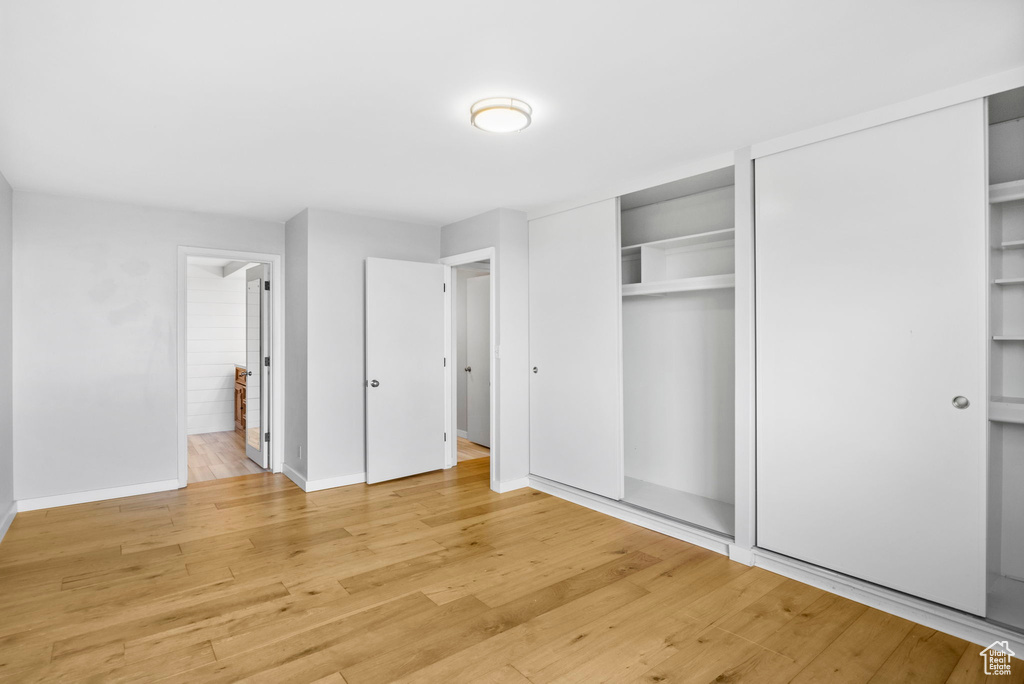 Unfurnished bedroom featuring baseboards, light wood finished floors, and multiple closets