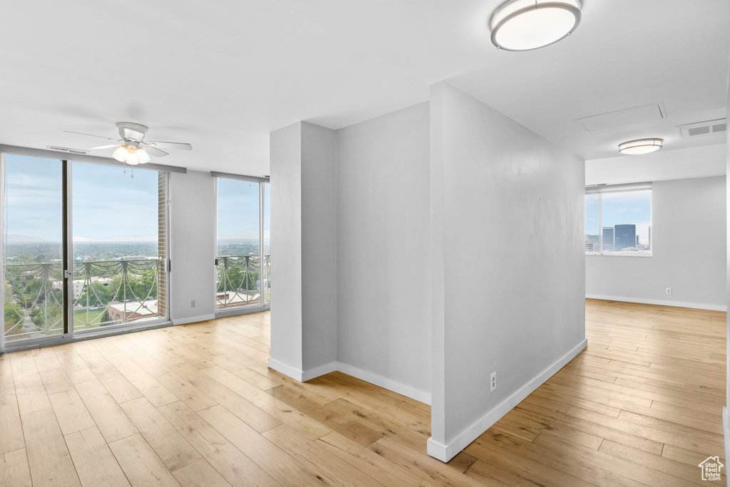 Unfurnished room featuring ceiling fan, hardwood / wood-style flooring, and a wealth of natural light