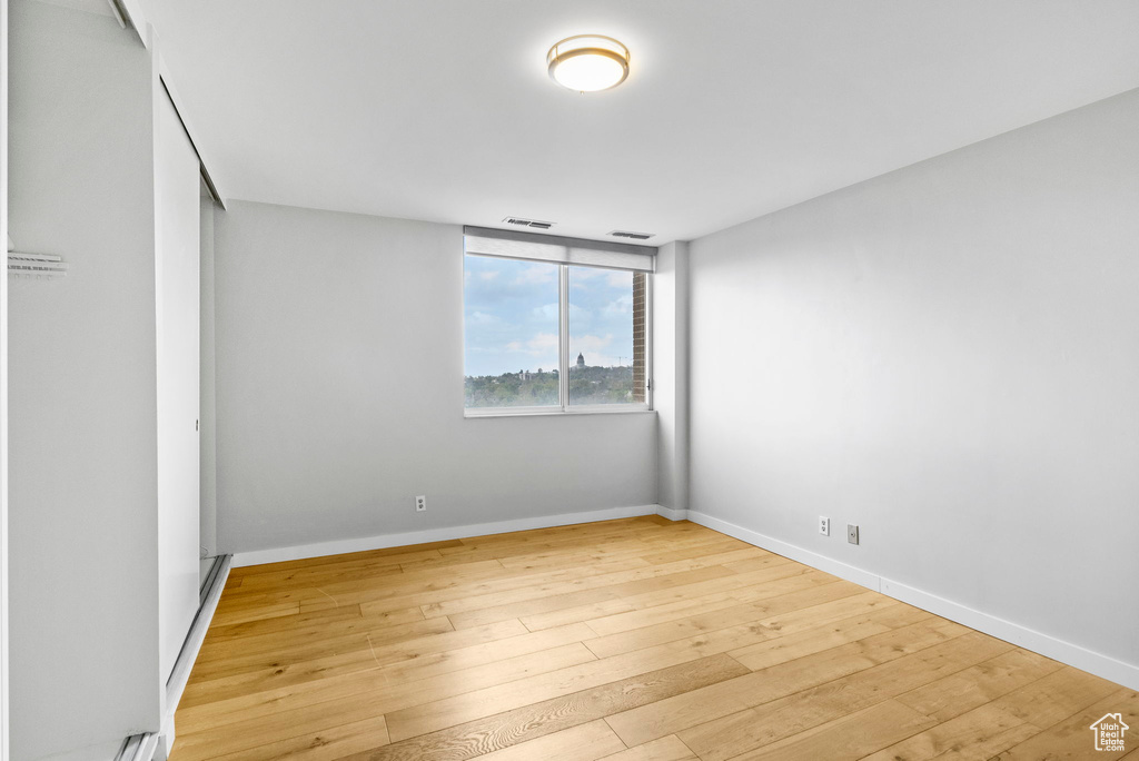 Unfurnished room featuring baseboards, visible vents, and wood-type flooring